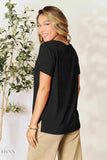 Smiling model wearing women's basic black t-shirt with short sleeves relaxed fit and beige pants