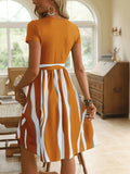 Woman wearing a striped tie waist dress with orange top and vertical white and rust stripes skirt