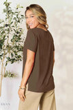 Smiling model wearing women's basic black t-shirt style in dark brown back view with relaxed fit and short sleeves