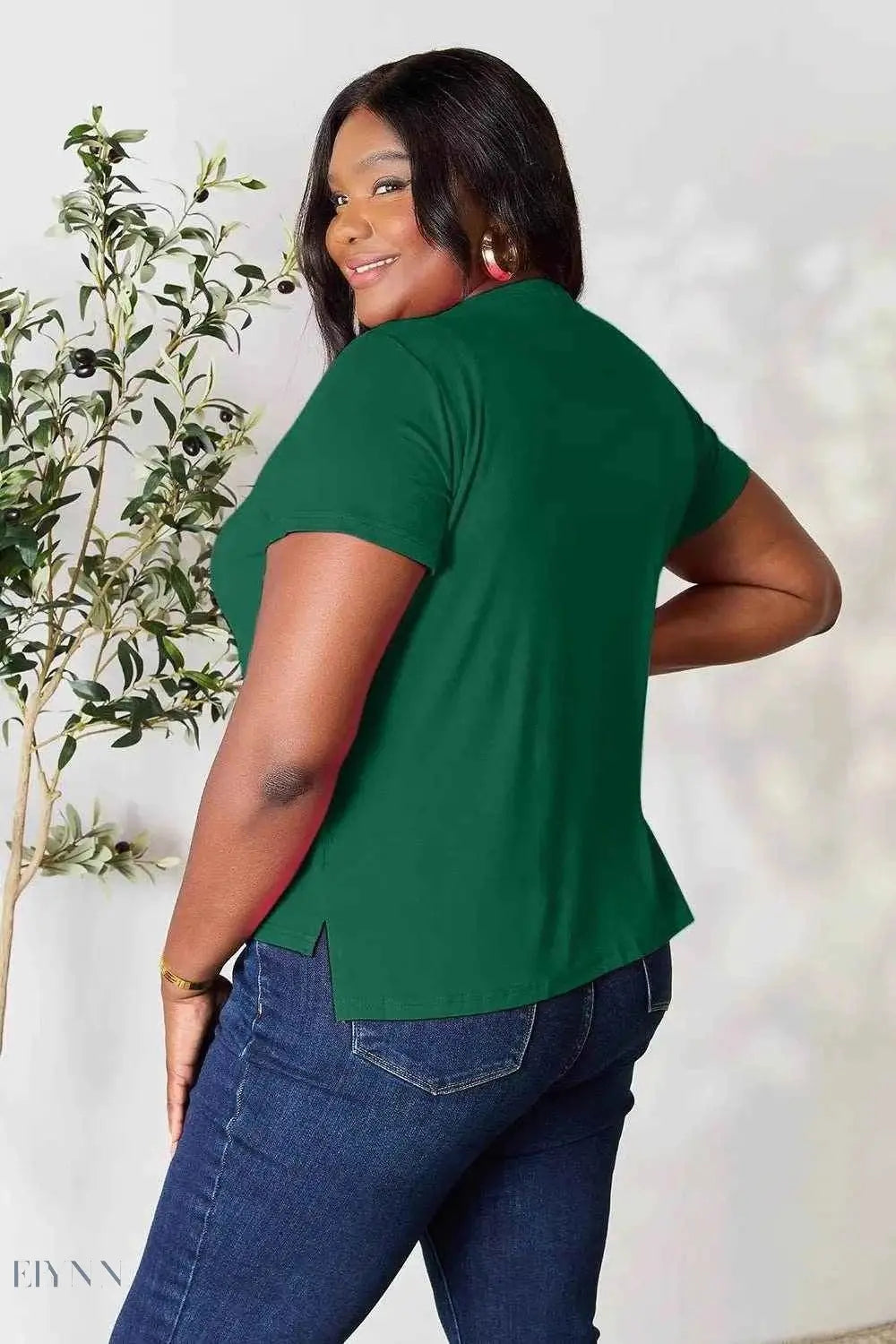 Plus size model wearing a short sleeve green top and jeans showcasing a women's basic black t-shirt listing by Trendsi