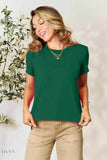 Model wearing green crewneck tee and khaki pants holding hem for women's basic black t-shirt listing