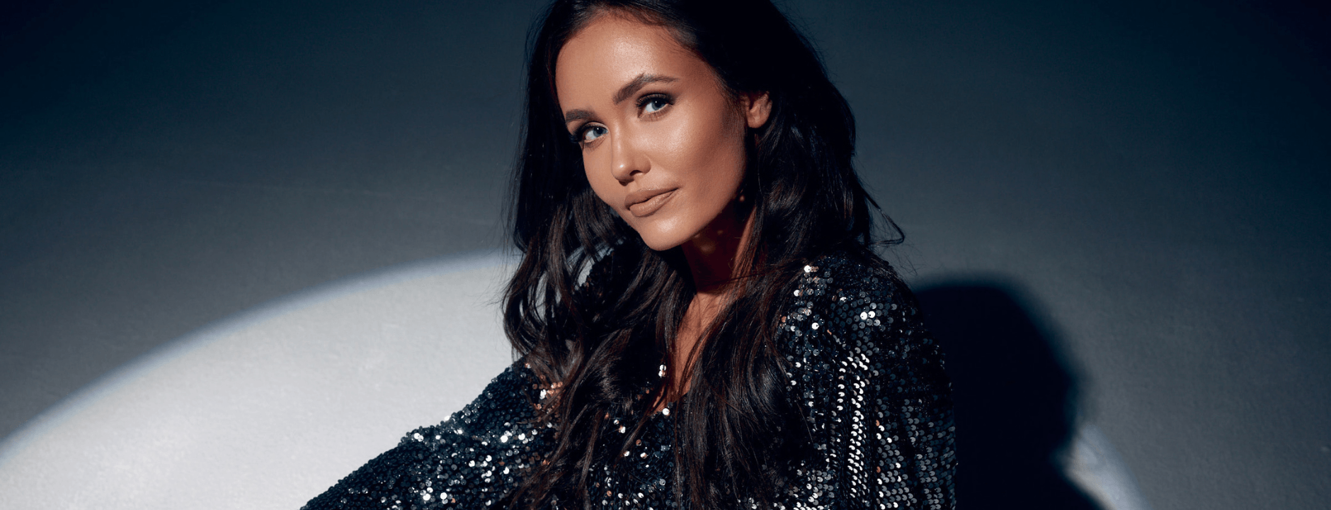 Woman wearing a sparkling black outfit against a dark background